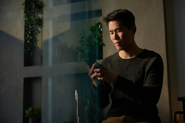 man looking at his phone near window